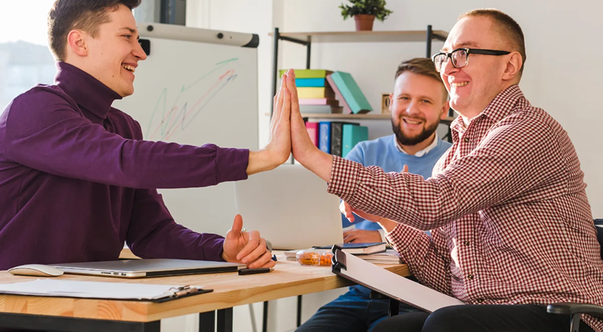 Carmel Care team members high-fiving in a collaborative office setting