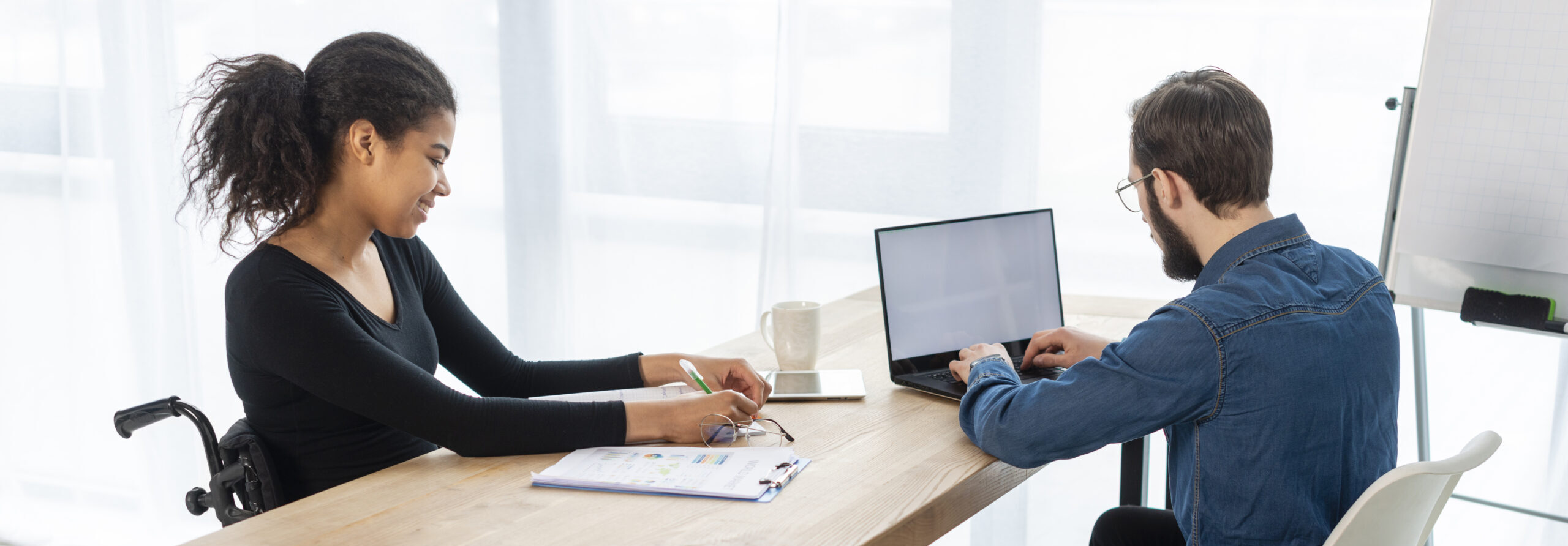 Support worker assisting a young participant at a desk